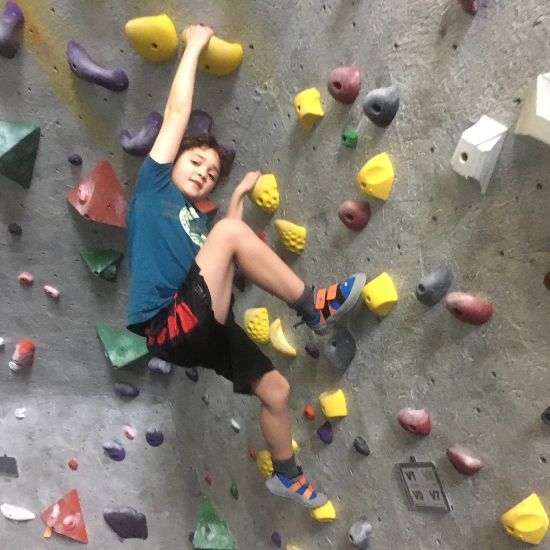 Young boy climbs yellow boulder at central rock gym worcester summer camp.
