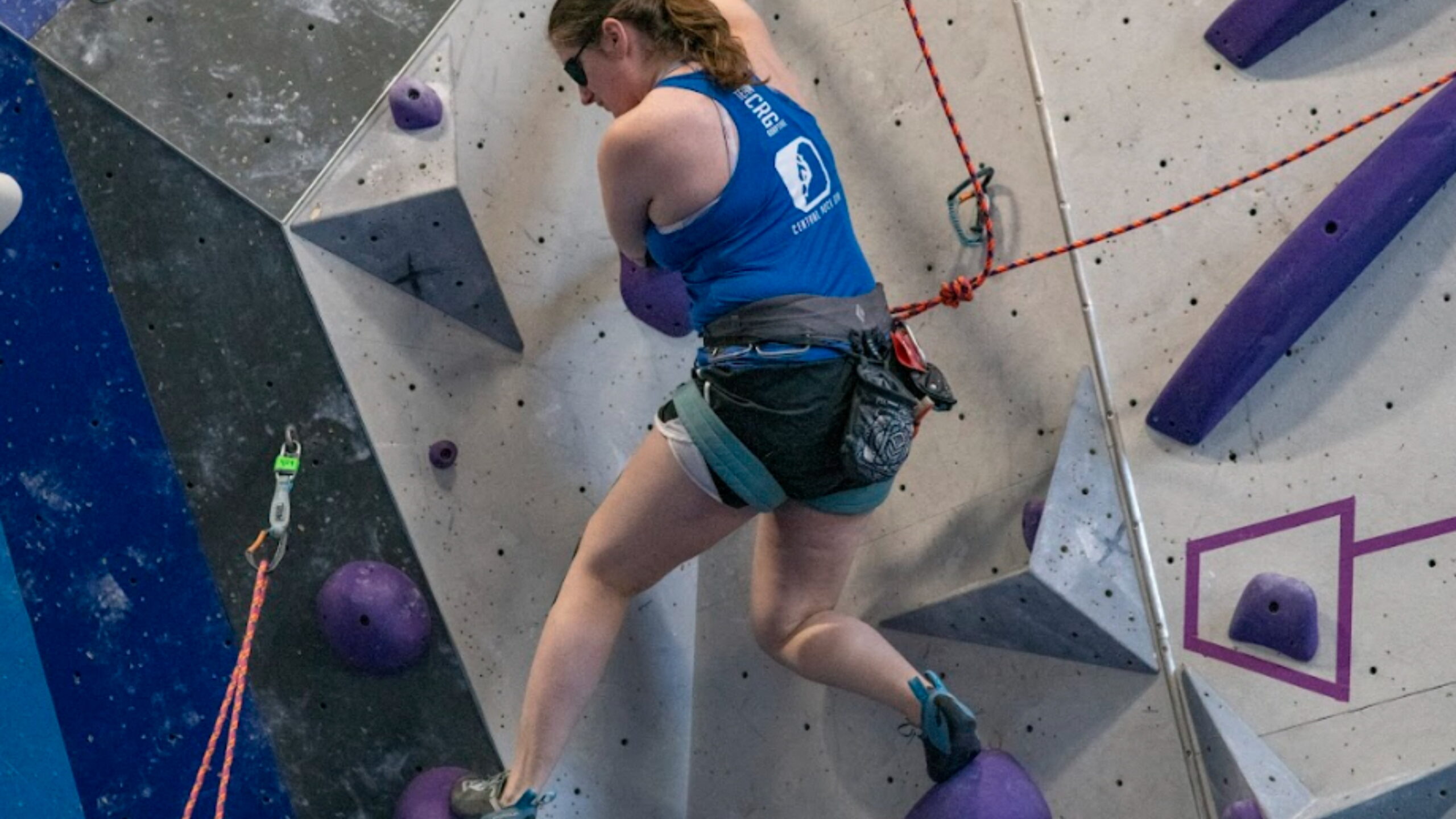 A Team Central Rock Gym visually impaired climber competes in an adaptive climbing event.