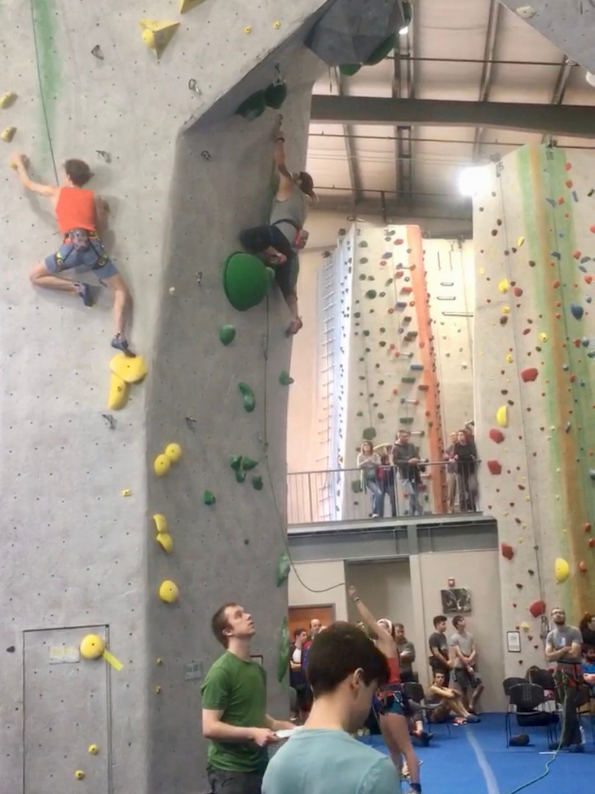 Two climbers work through their routes while competing in a rope competition.