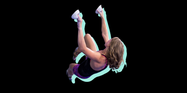 A woman climbs and leans to the side, looking toward the next hold.