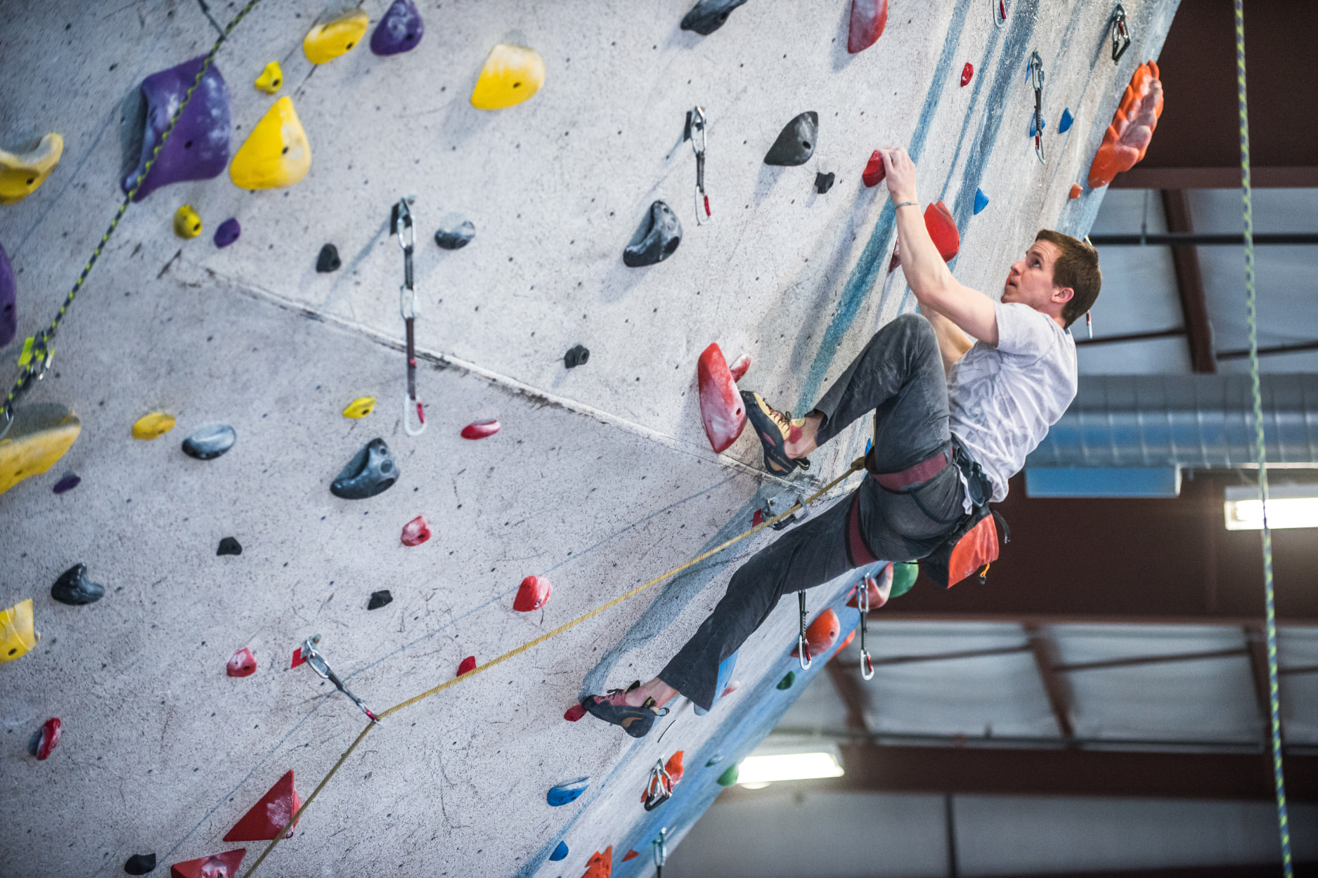 A man lead clips up over the lip of the steep overhanging wall at Central Rock Gym.
