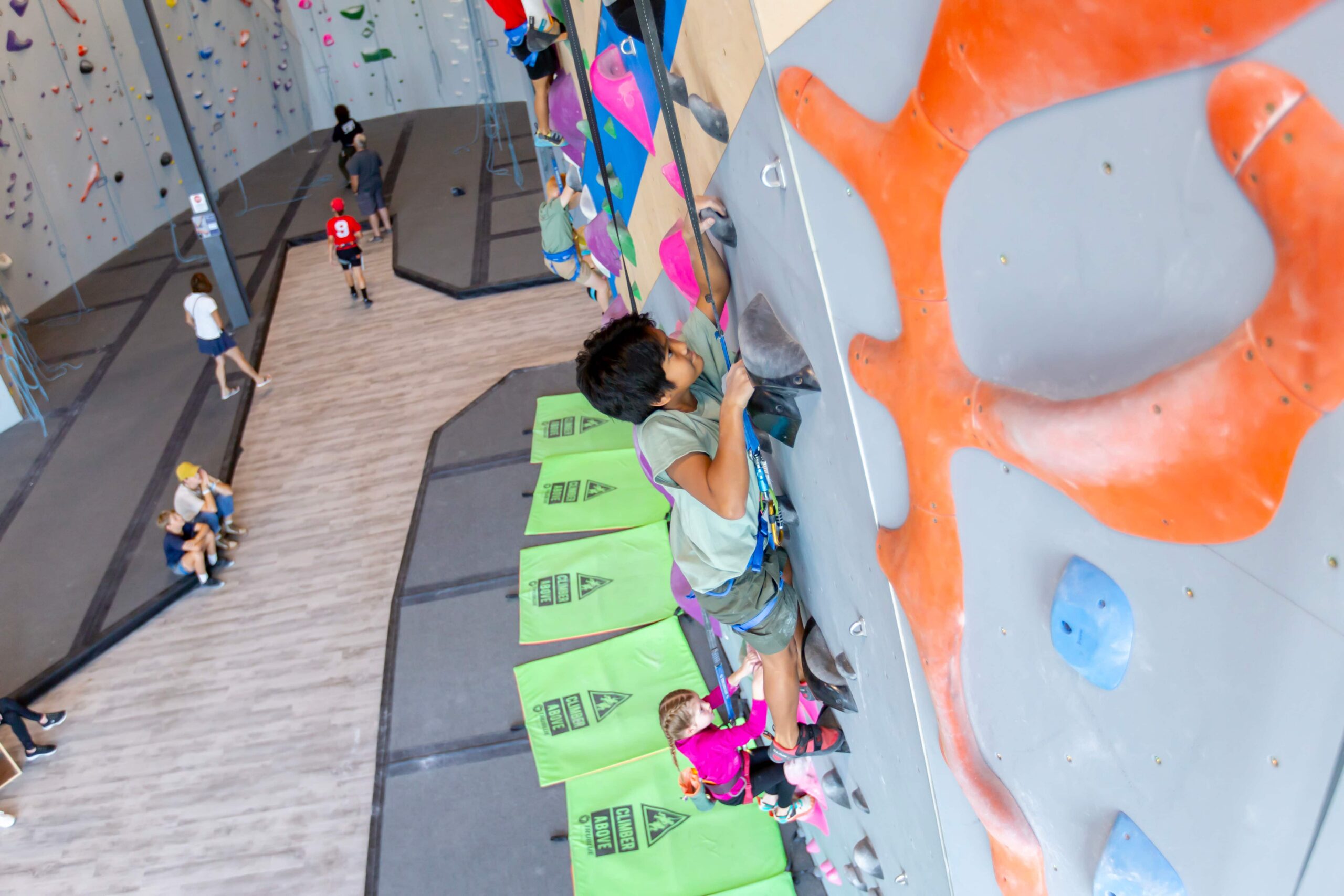 A young boy holds on tightly to the wall as he auto belays.