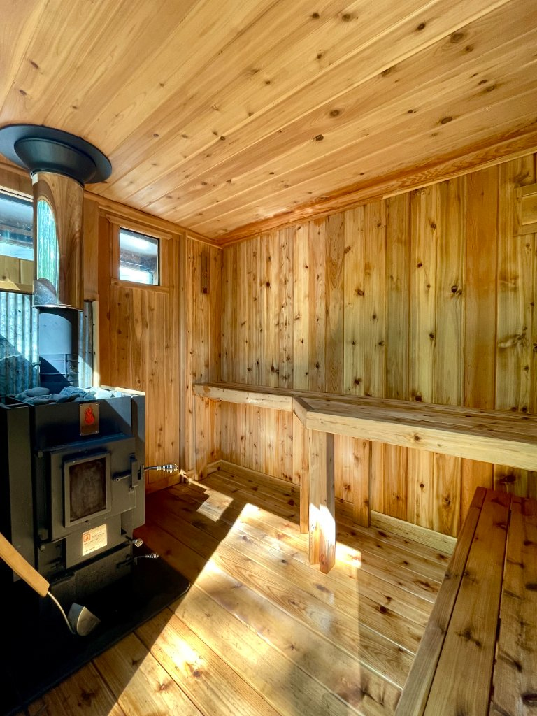 A sauna with a furnace and two levels of benches oriented perpendicularly.