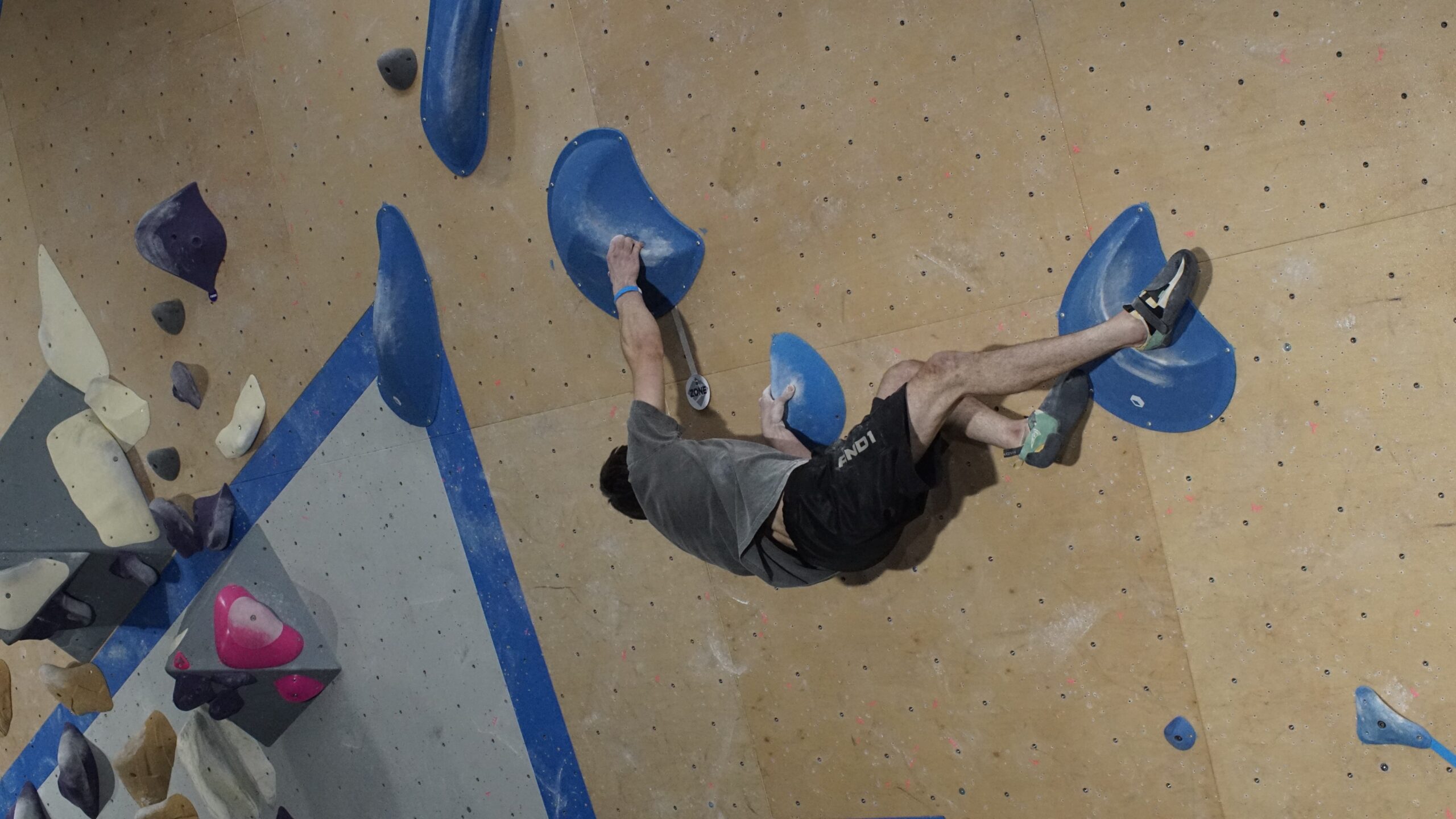 a man sideways as he is bouldering at central rock gym