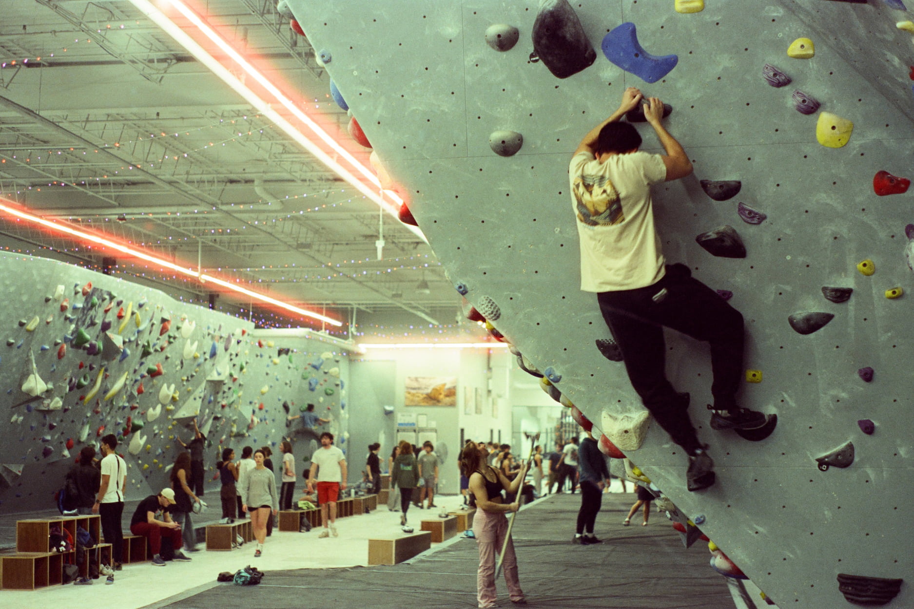 A man boulders on the vertical wall next to the arete. He is pulling upwards through hands matched on a hold at Central Rock Gym.