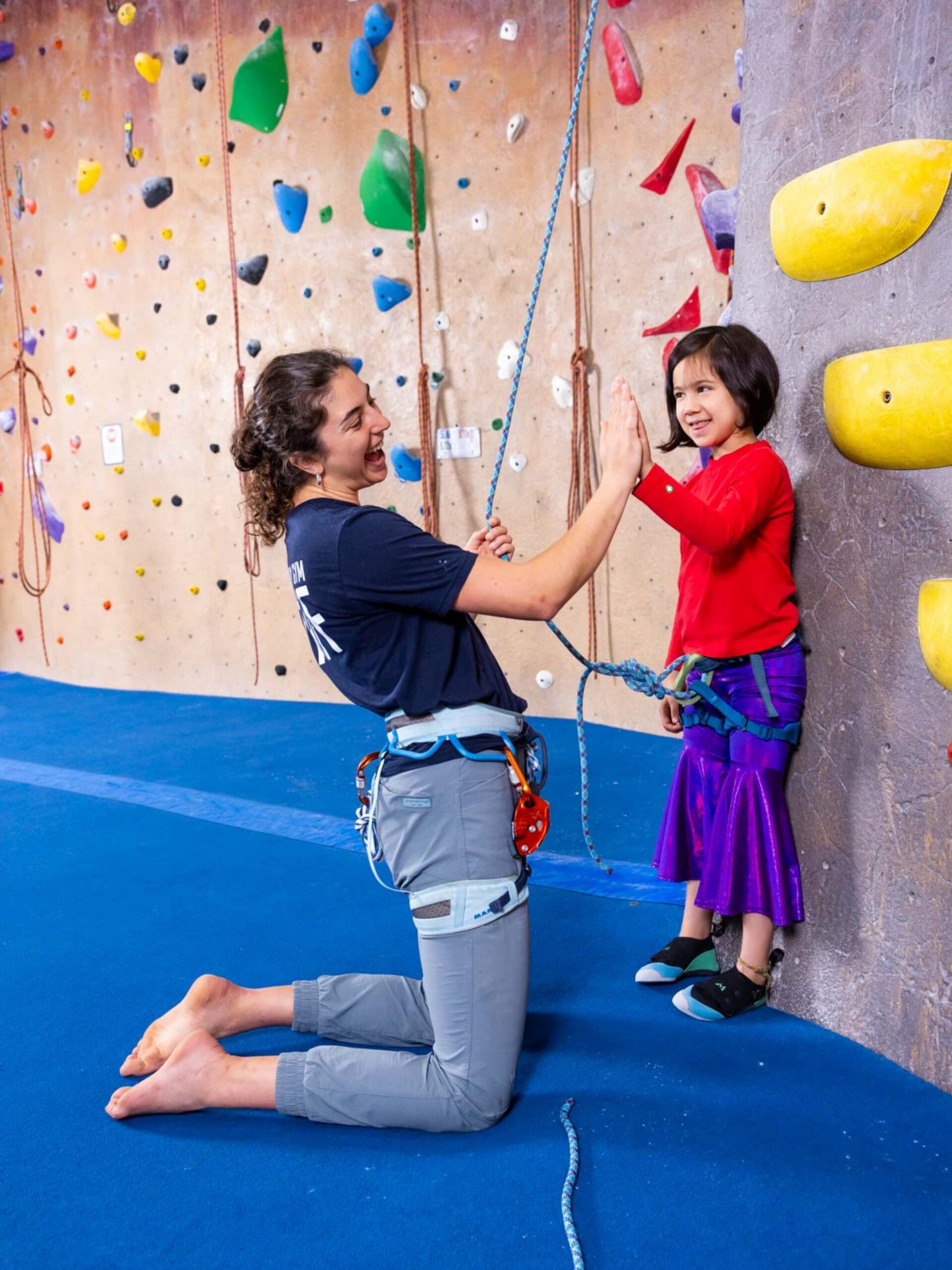 A Central Rock intrustor helping a little girl climb at Central Rock Gym
