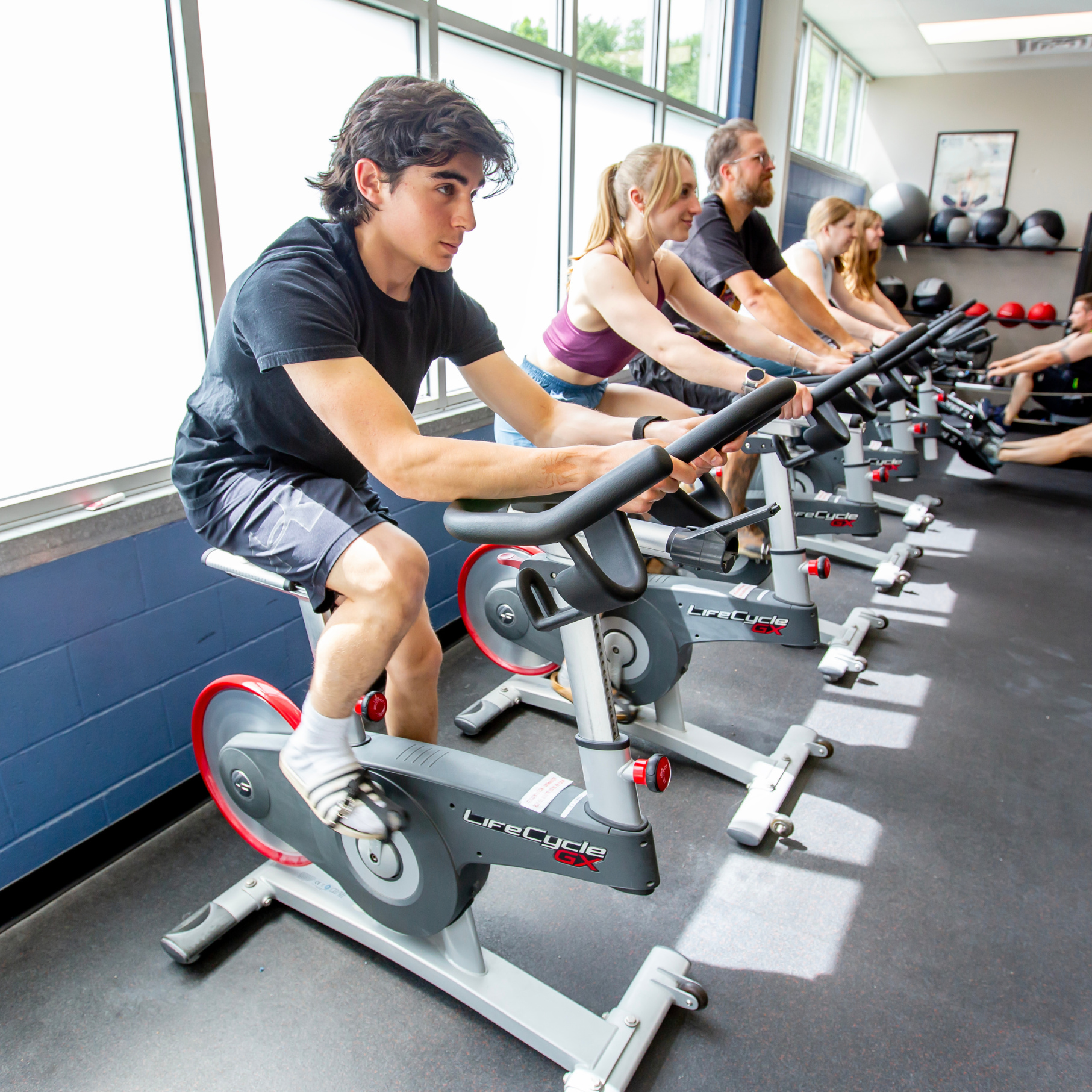A group of people workout together on bikes during a fitness class at Central Rock Gym.