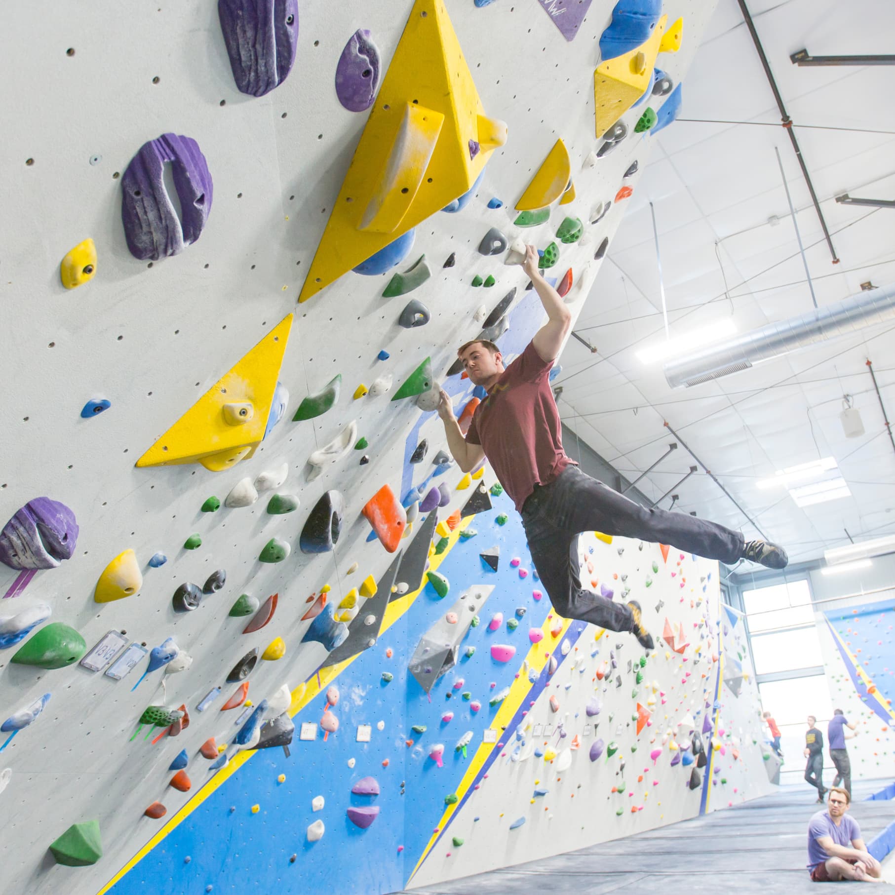 a man is bouldering and leaps to the next climb at central rock gym