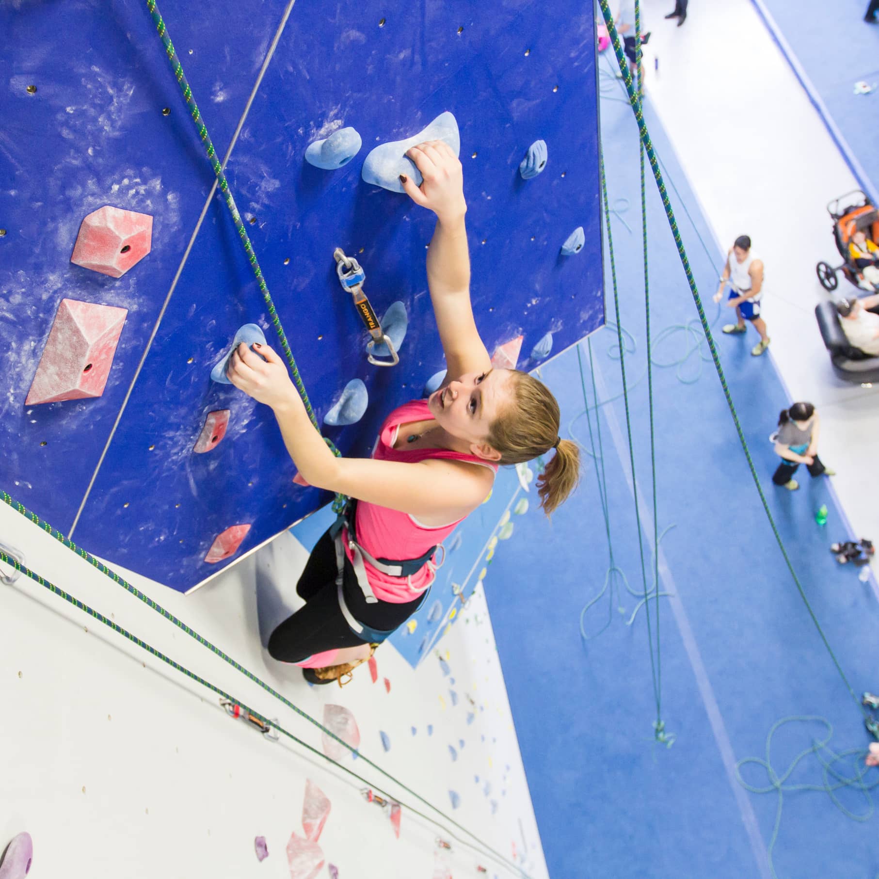 A girl is Top rope climbing at Central Rock Gym