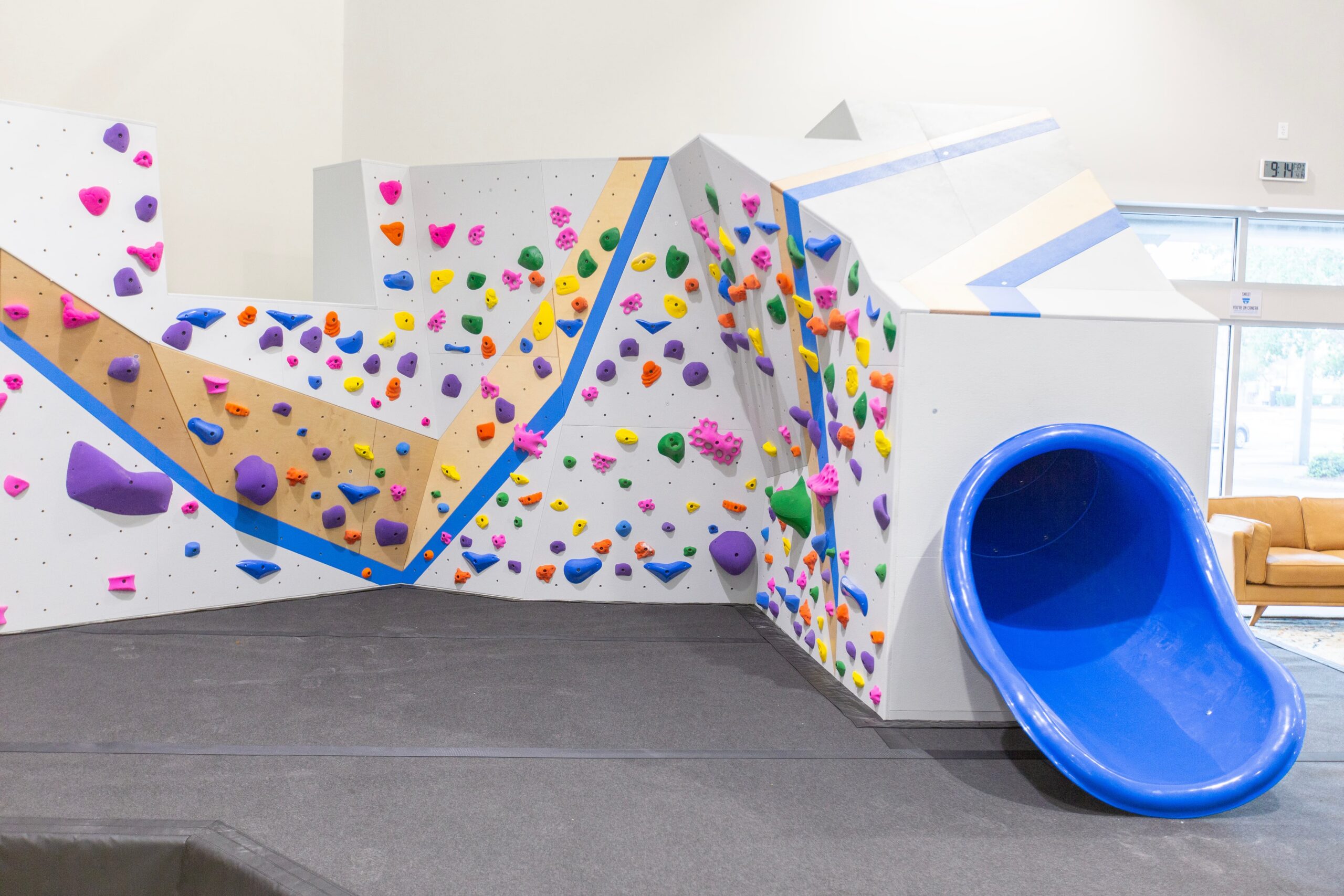 A rock wall that has a slide attached at central rock gym