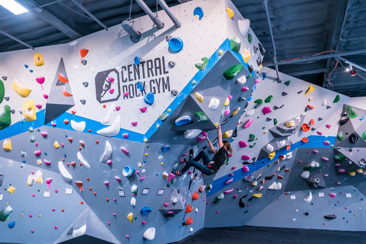 a women is bouldering at central rock gym